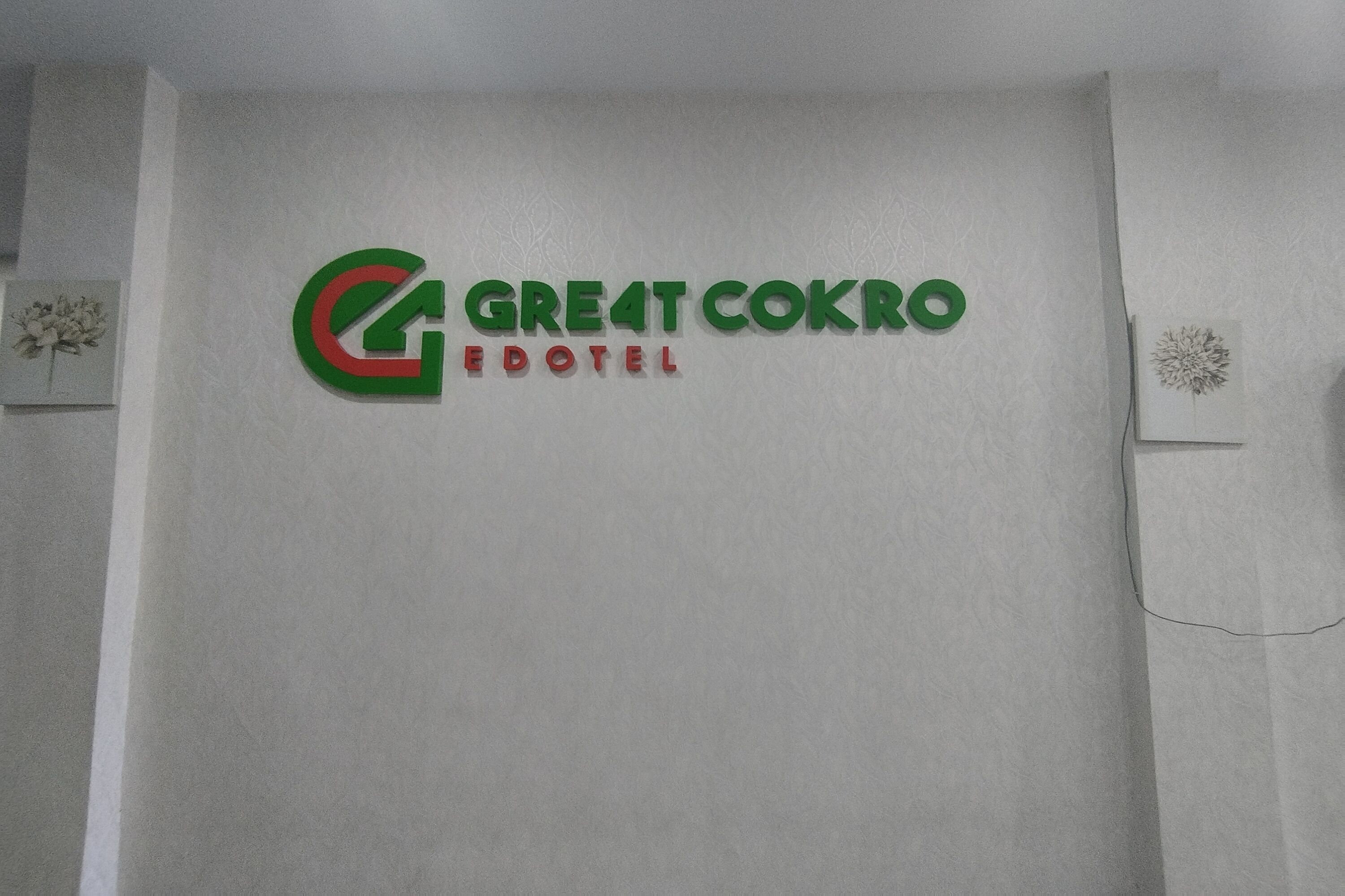 Een muur met het logo van het Great Cokro Hotel.