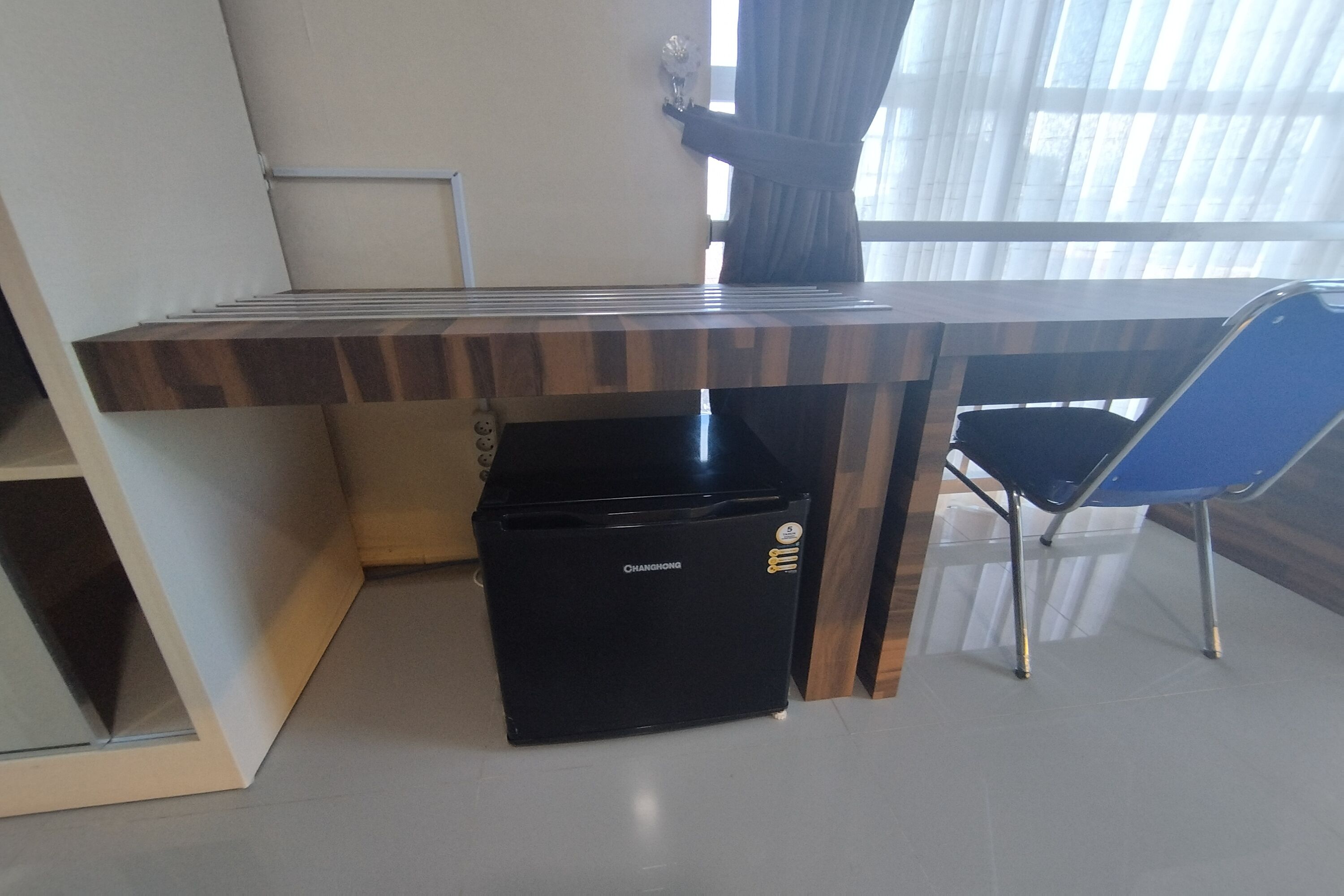 A modern room with a built-in desk, a black trash bin, and a blue chair.