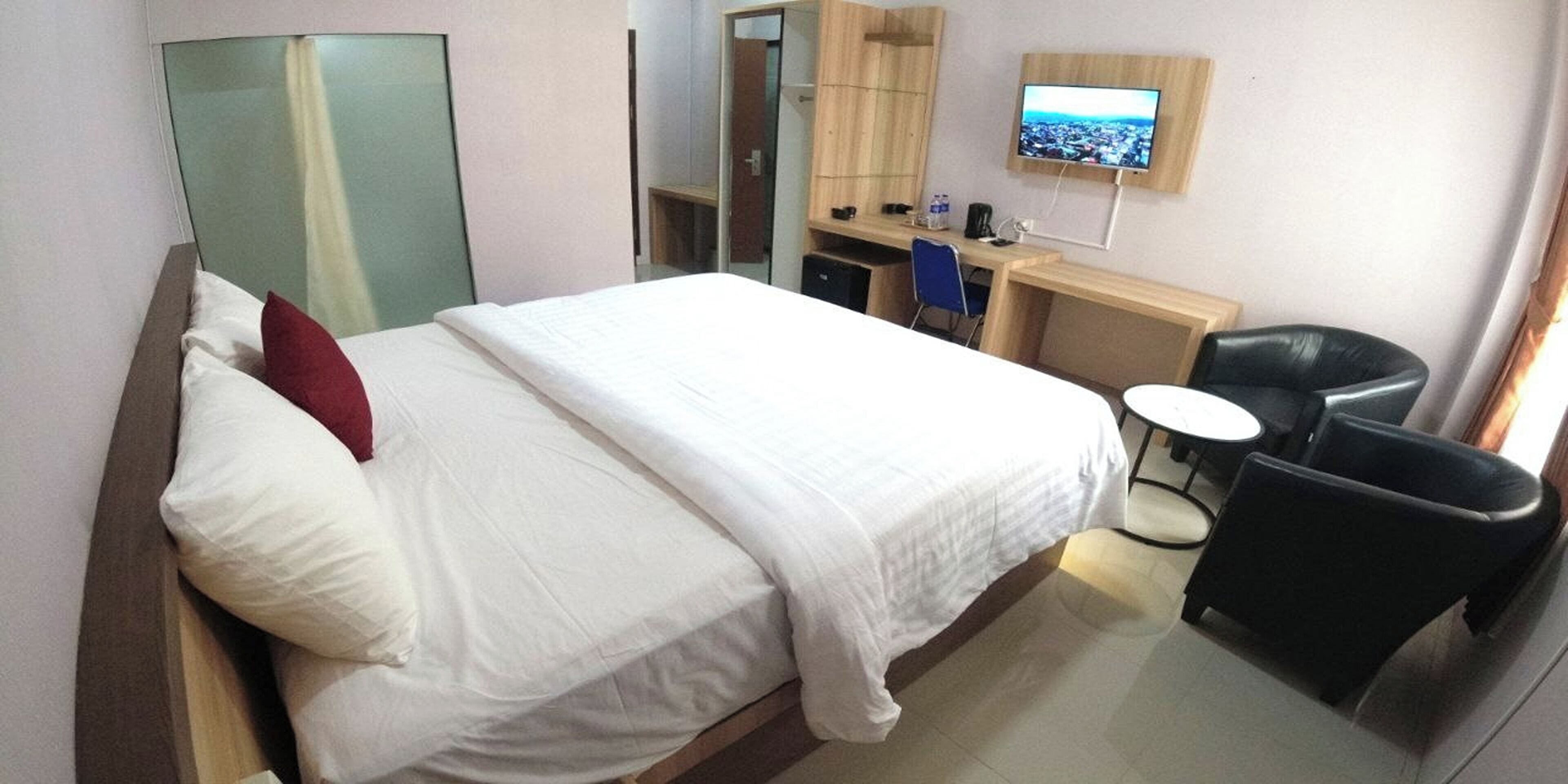 Een hotelkamer met een bed, bureau, stoel, televisie en spiegel.