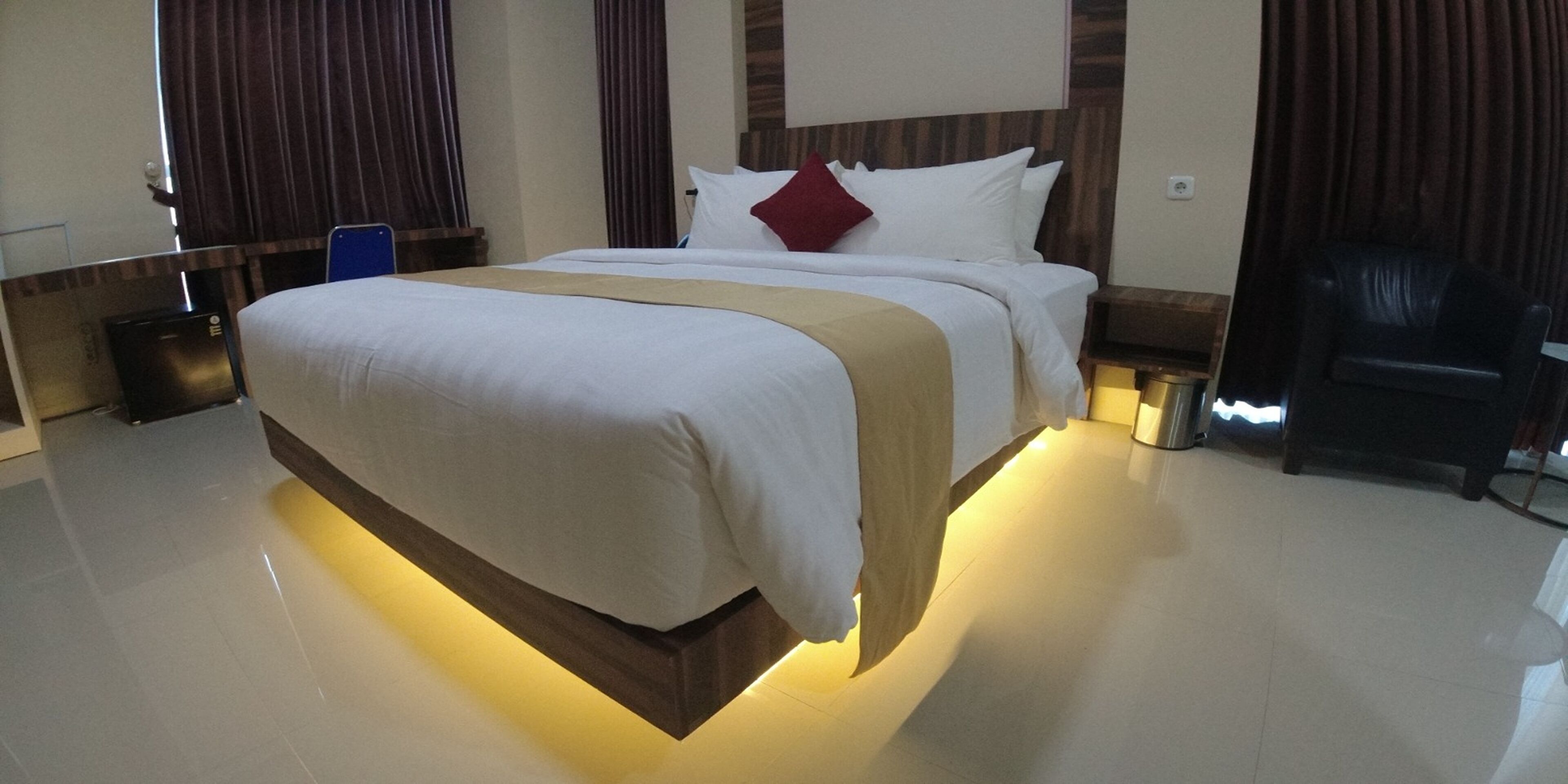 Une chambre d’hôtel avec un grand lit, une tête de lit en bois et un design moderne.