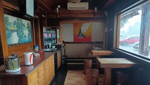Interior acogedor de un restaurante con armarios de madera, una barra con electrodomésticos de cocina y un amplio ventanal con vistas a la calle.