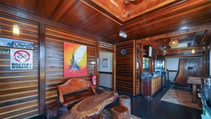 Interior de madera con una mesa de recepción, un banco y un cartel que indica prohibido fumar.