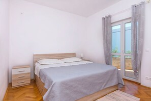 Une chambre Ă coucher comprenant un lit, une table de chevet, une commode et une fenĂȘtre avec des rideaux.