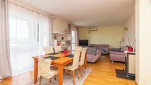 A living room with a wooden dining table, two sofas, a TV, and a potted plant. - Apartment Duce Beach (Duce)