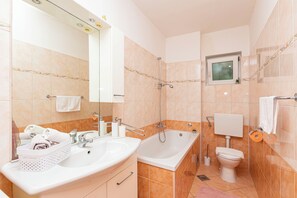 A modern bathroom with two sinks, a bathtub, and a toilet. - Apartment Duce Beach (Duce)