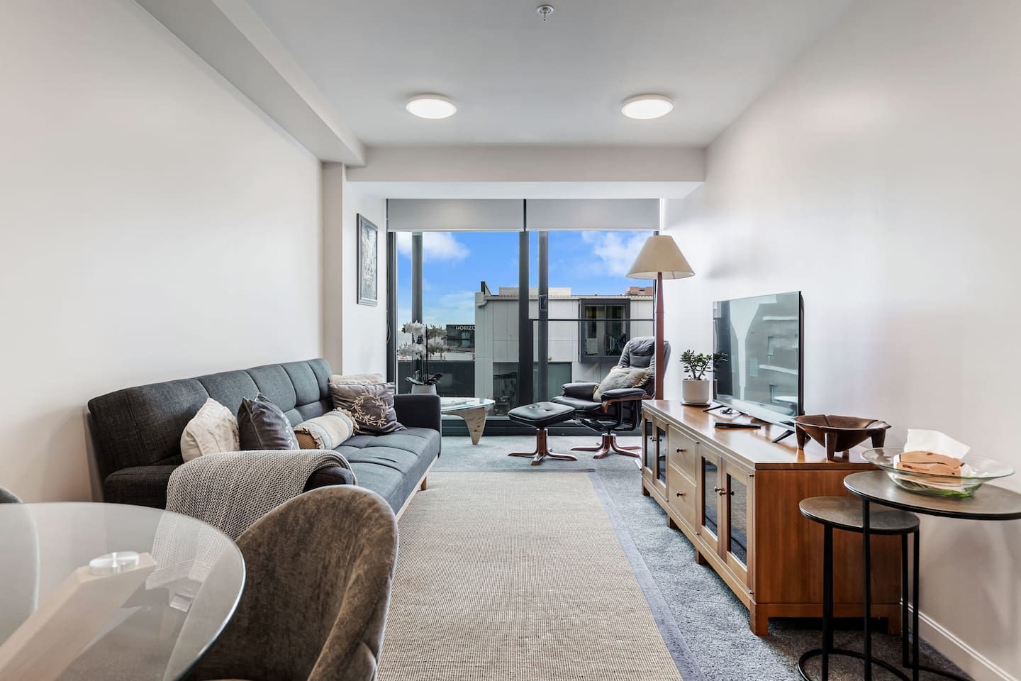Un salon moderne comprenant un canapé, un fauteuil et un coin repas avec une table et des chaises.