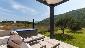 A patio with lounge chairs and a hot tub, overlooking a lush green landscape and hills. - House Madonna di Smovo (Gata)