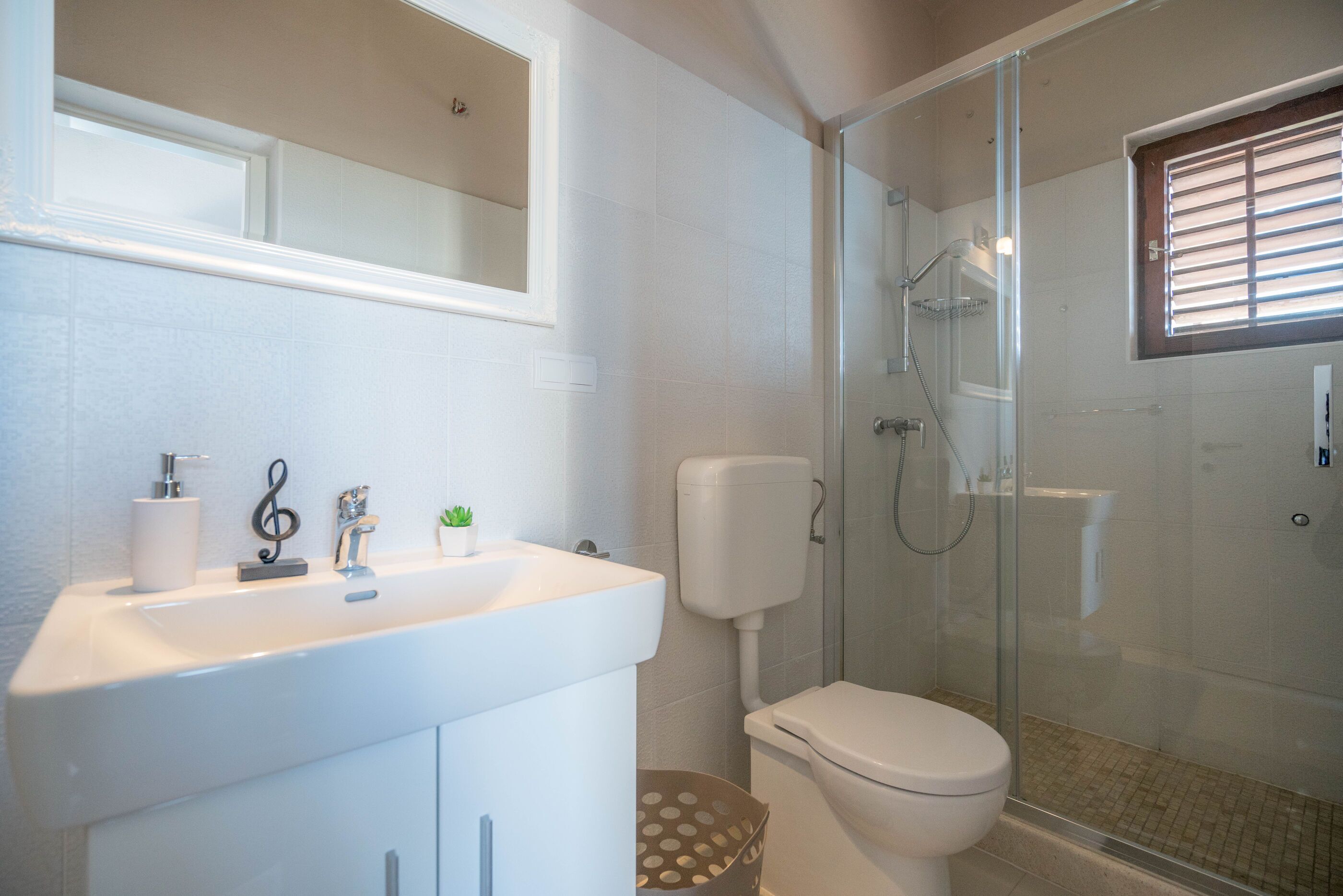 A bathroom with a white sink, toilet, and glass-enclosed shower.