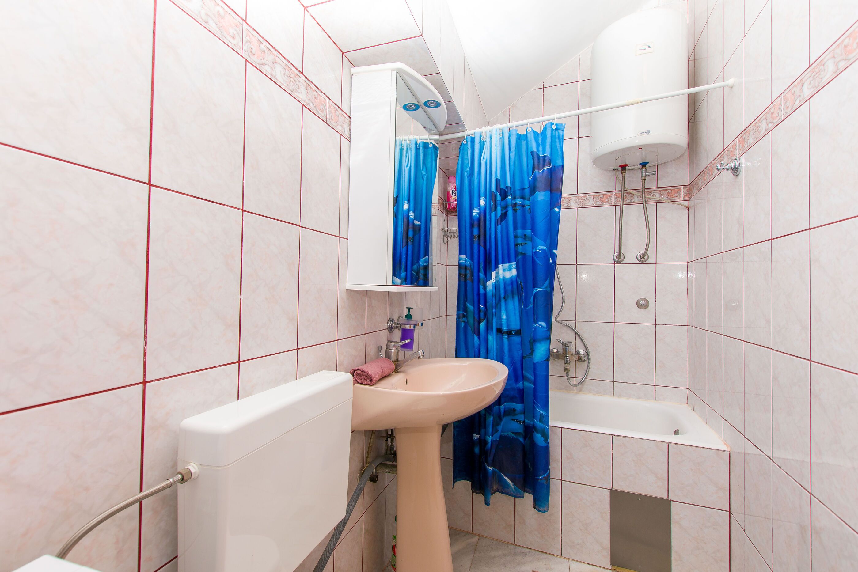 A bathroom with a sink, toilet, bathtub, and shower curtain.