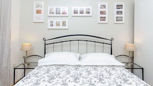 Una cama bien tendida con una colcha estampada floral, un cabecero de metal negro y dos lámparas de noche.