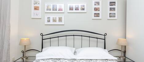 A neatly made bed with a floral-patterned bedspread, a black metal headboard, and two bedside lamps.