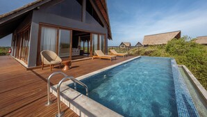 A modern villa with a swimming pool, lounge chairs, and a thatched-roof structure in the background. - Kotiyagala Luxury Villas (Palatupana)