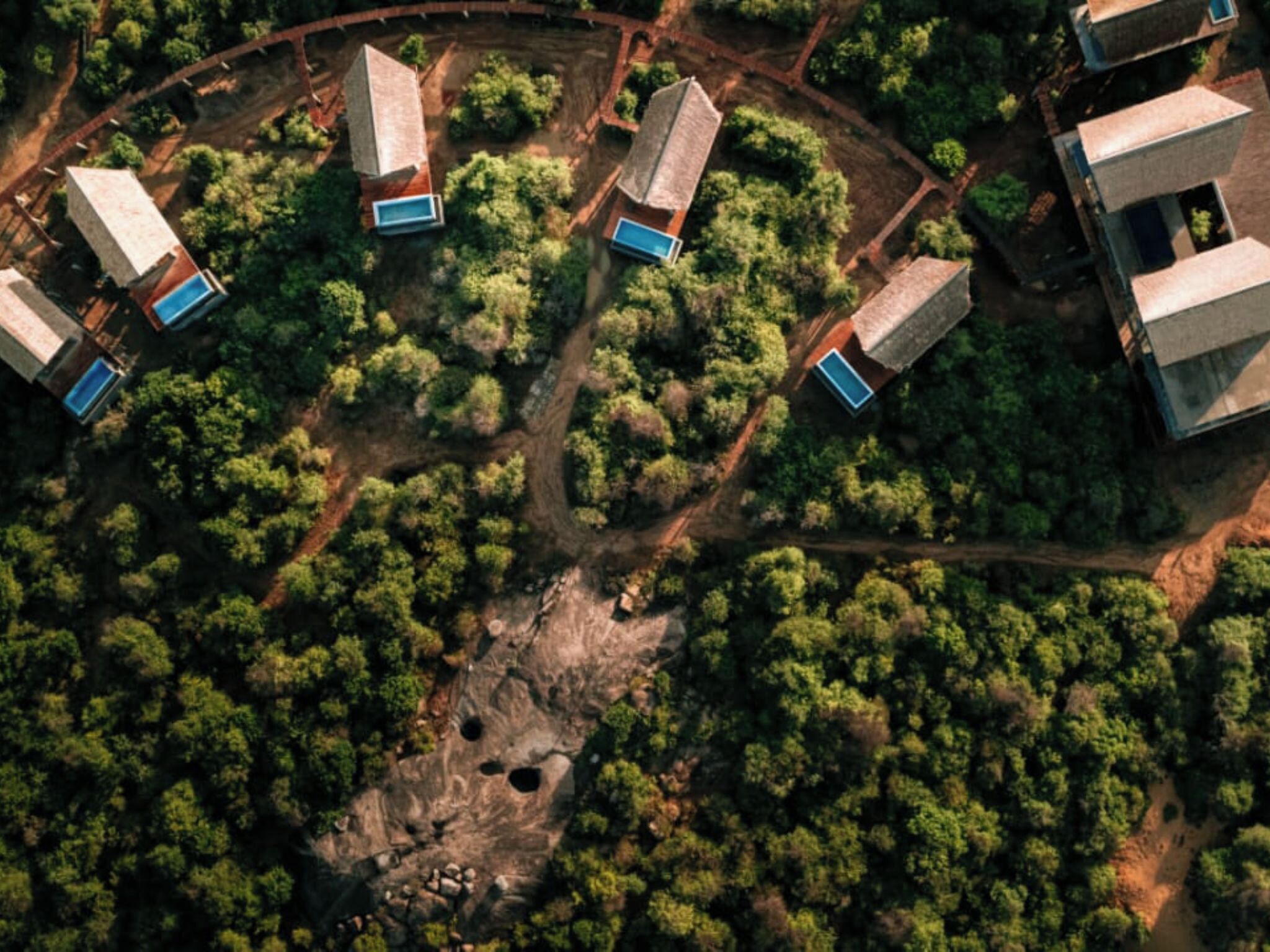 Una vista aerea di un resort con diversi edifici immersi in una fitta foresta.