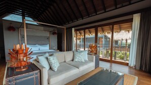 A modern hotel room with a large bed, a sofa, a glass coffee table, and a view of the outdoors. - Kotiyagala Luxury Villas (Palatupana)