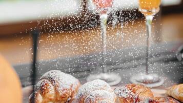 Pastries dusted with powdered sugar and a glass of orange juice on a table.
