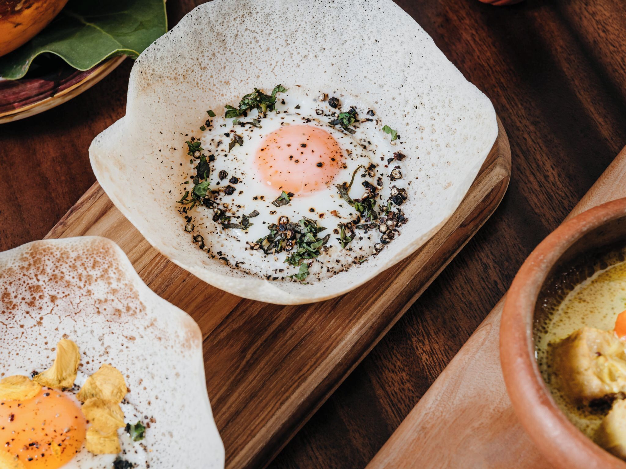 A breakfast dish with an egg and herbs on a ceramic plate.