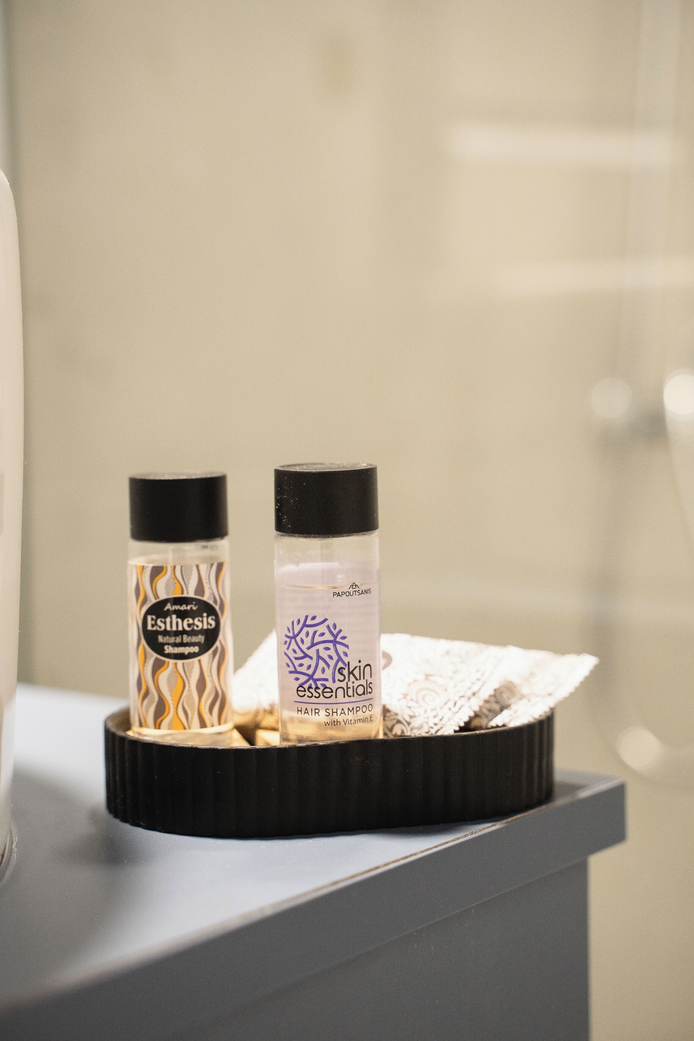 Two hair care products on a black tray in a bathroom.