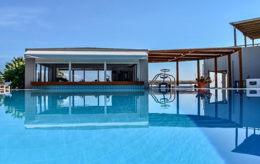 A clear blue pool with a covered seating area and a pergola.