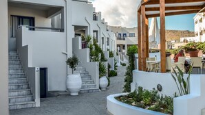 Een modern woongebouw met een smalle binnentuin, witte muren en een houten pergola.