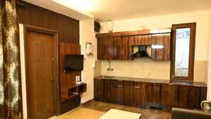 Una cocina compacta con armarios de madera, microondas integrado y una ventana sobre el lavamanos.