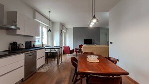 A modern kitchen with white cabinets, a wooden dining table, and a red chair.