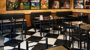 A restaurant interior with wooden ceiling, black and white checkered floor, black and white chairs, and chandeliers. - Hotel Priyadarsini (Bankura)