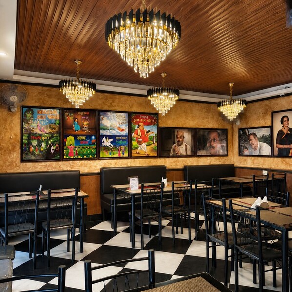 A restaurant interior with wooden ceiling, black and white checkered floor, black and white chairs, and chandeliers.