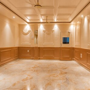 A spacious room with a marble floor, cream-colored walls, and a ceiling with recessed lighting and a central light fixture.