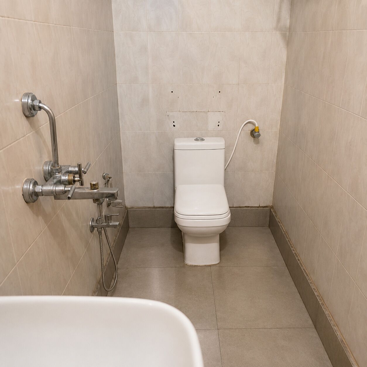 A small, tiled bathroom with a toilet, a shower, and a sink.