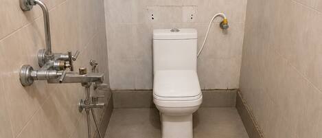 A small, tiled bathroom with a toilet, a shower, and a sink.