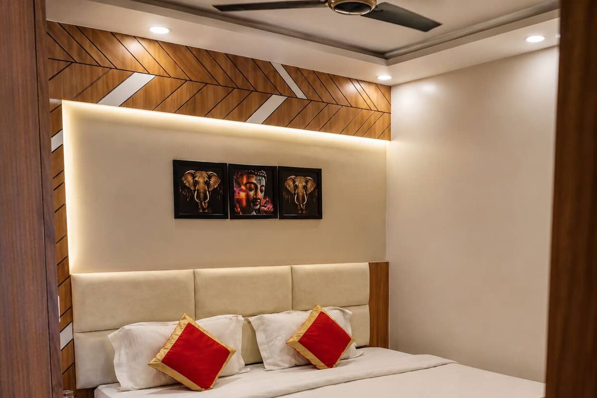 A bedroom with a bed, nightstands, a wooden headboard, and wall art.