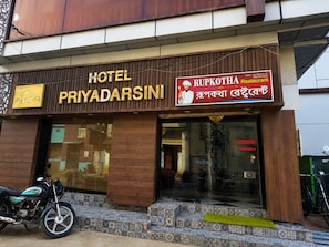 A hotel named 'PRIYADARSINI' with a sign for 'RUPKOTHA Restaurant' and a motorcycle parked outside.