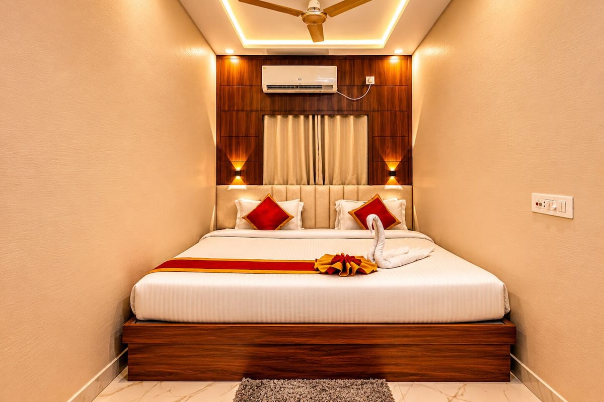 A bedroom with a bed, a ceiling fan, an air conditioning unit, and a power outlet on the wall.