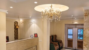 A hotel lobby with a marble floor, a reception desk, a chandelier, and a seating area with patterned upholstery. - Hotel Priyadarsini (Bankura)