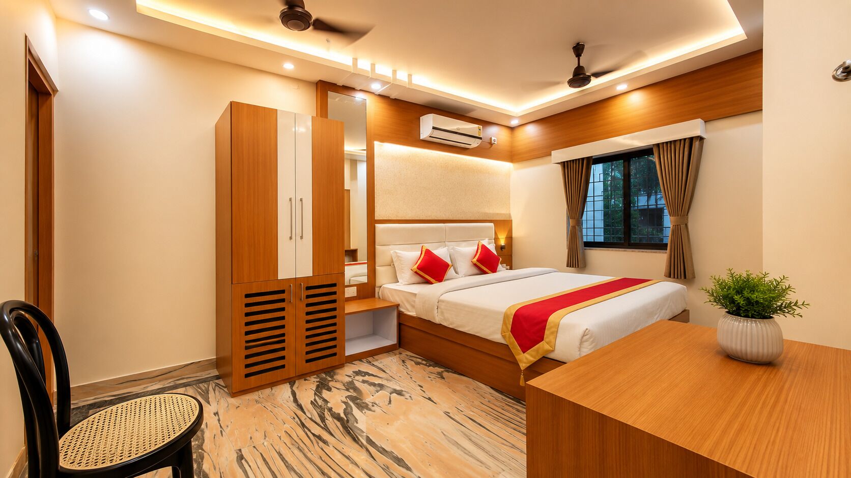 A hotel room with a bed, a desk, a chair, an air conditioning unit, and a window with curtains.