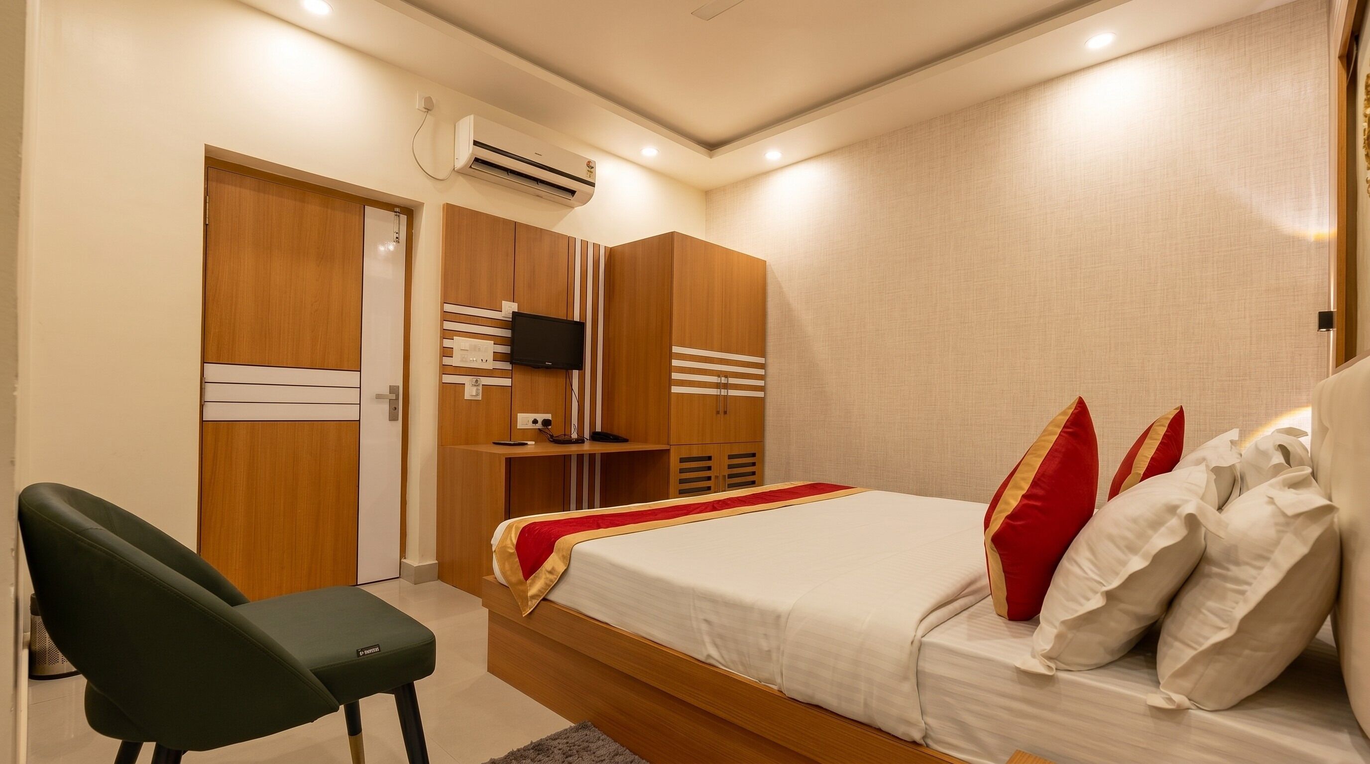 A bedroom with a bed, a desk, a chair, and a TV on a wall.
