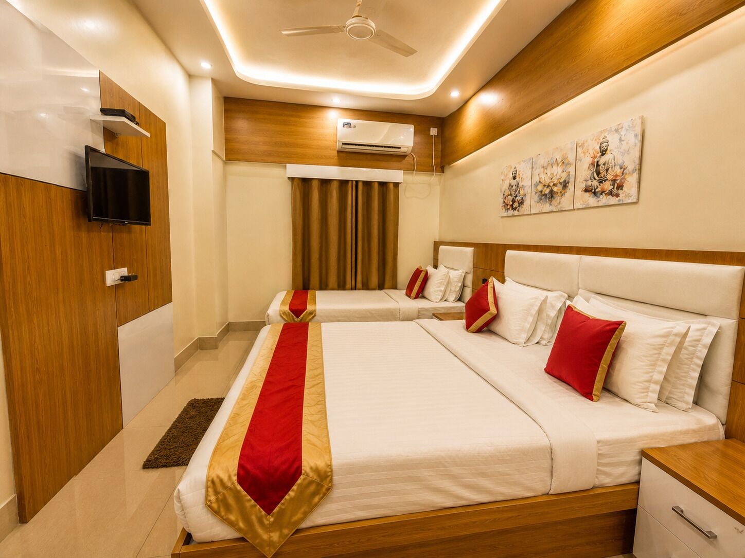 A hotel room with a large bed, a television, an air conditioning unit, and artwork on the wall.