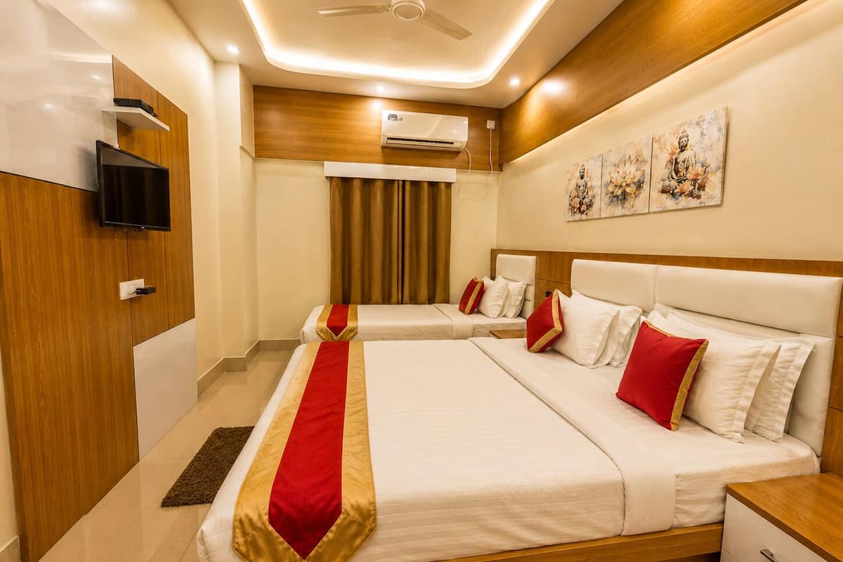 A hotel room with a large bed, a television, an air conditioning unit, and artwork on the wall.