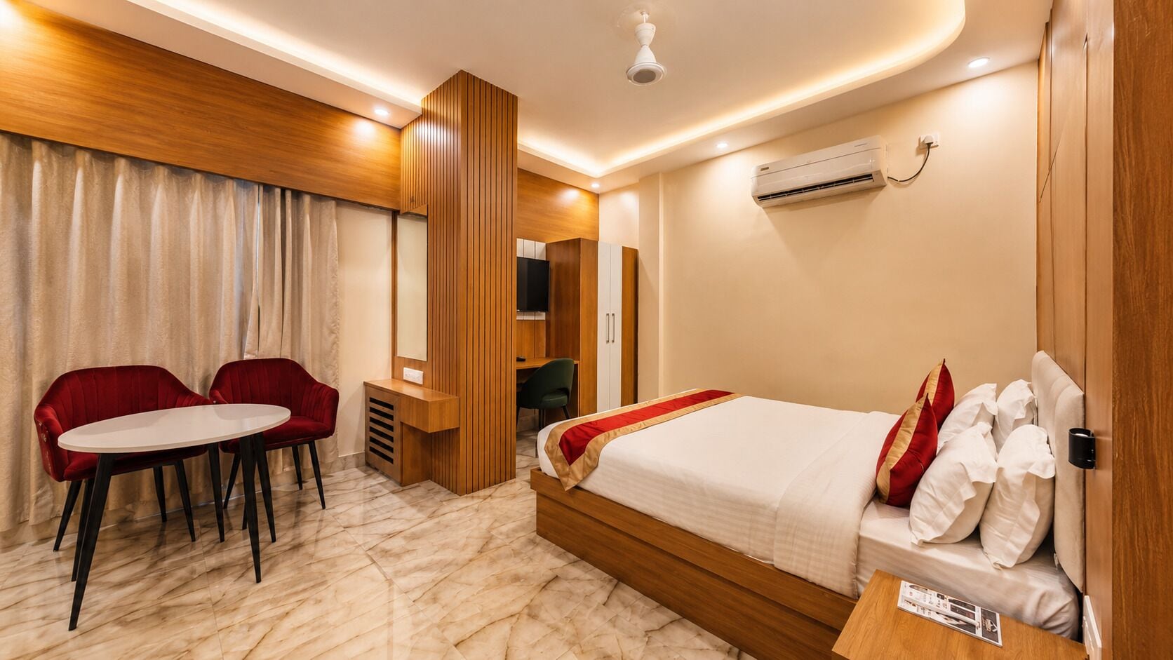 A hotel room with a bed, a desk, a chair, and an air conditioning unit.