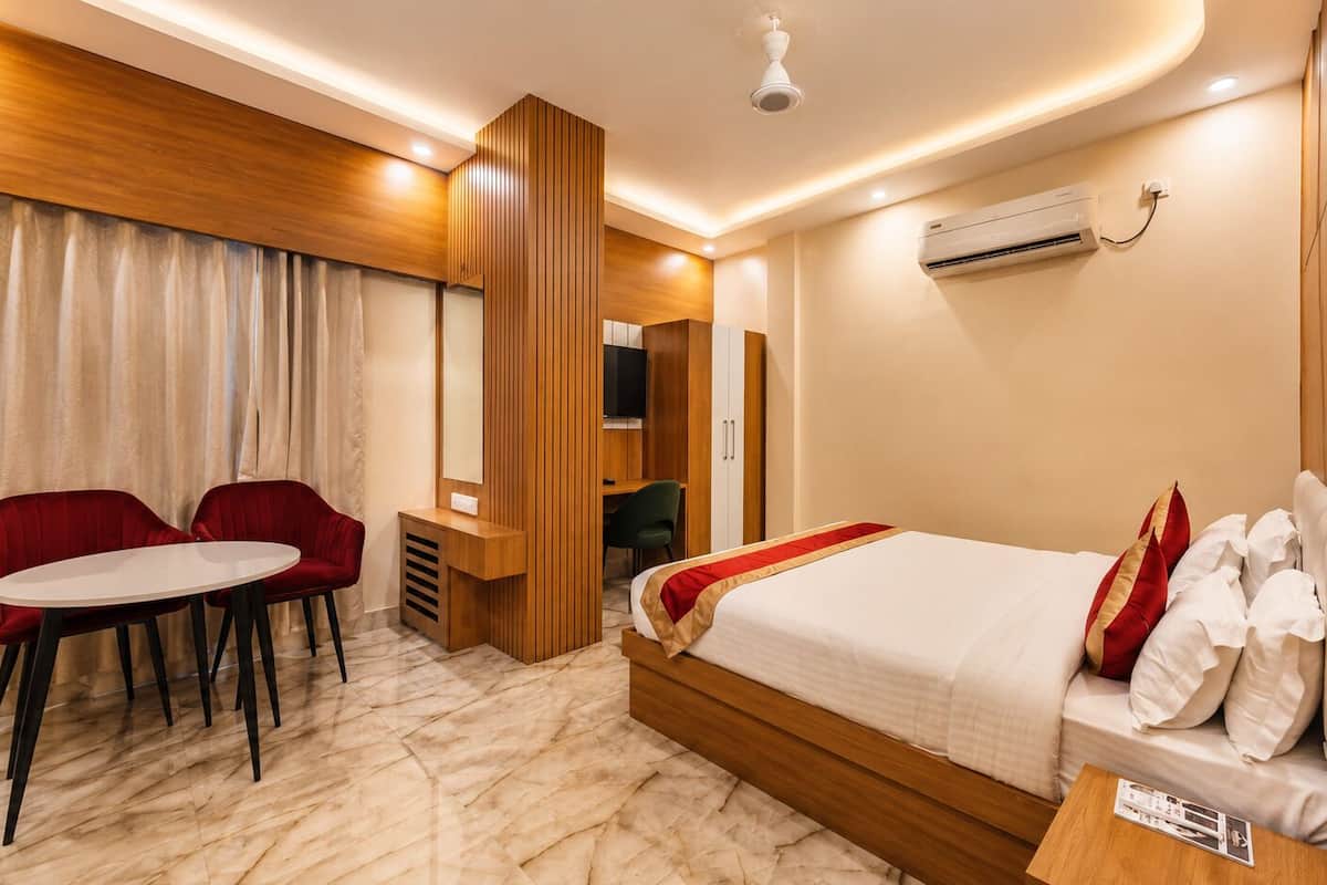 A hotel room with a bed, a desk, a chair, and an air conditioning unit.
