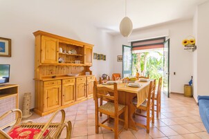Un comedor con una mesa y sillas de madera, un televisor a la izquierda y un aparador con vajilla.