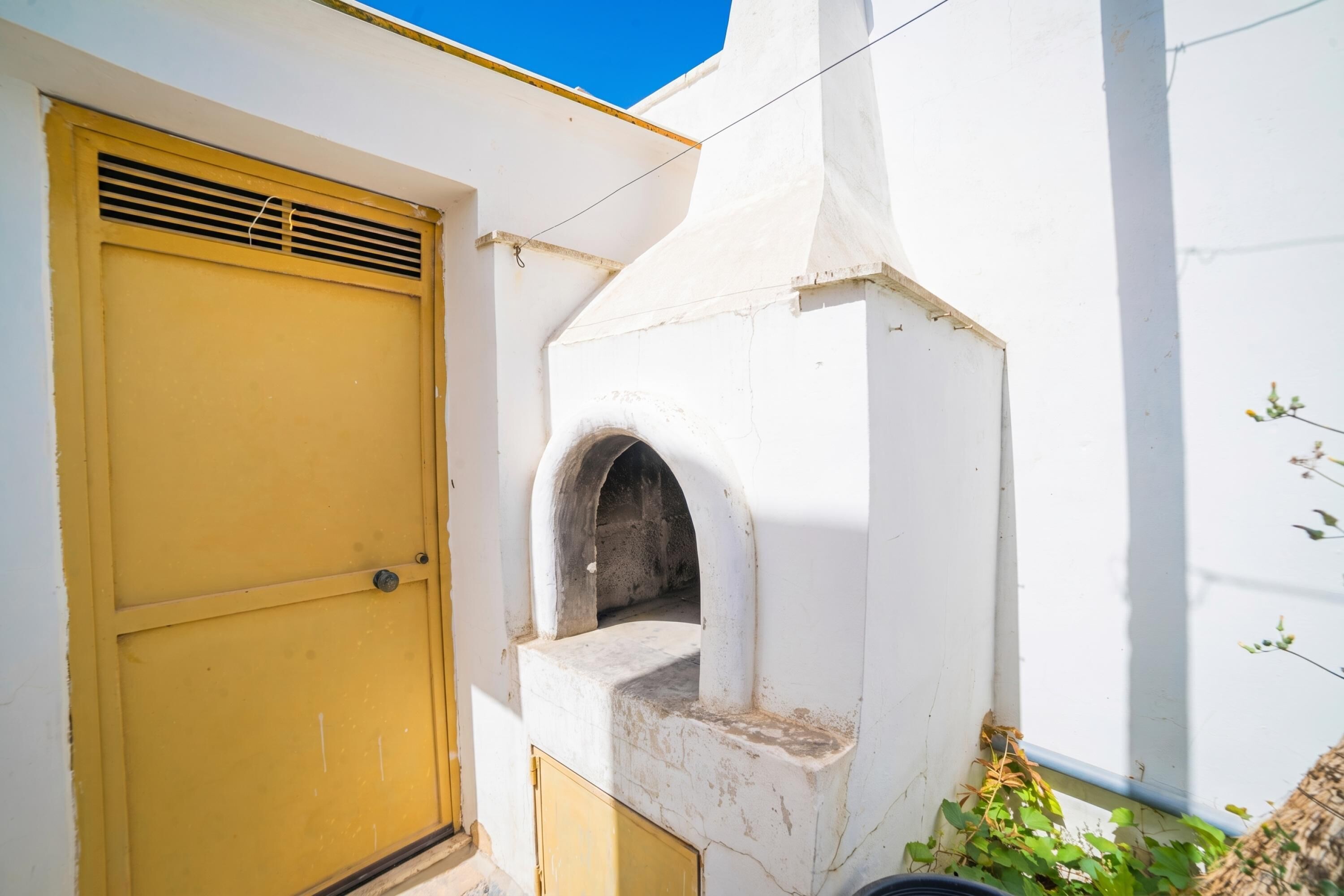 A white building with a yellow door and a small arched window.