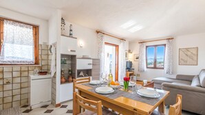 A dining area with a wooden table, chairs, and a view of the living room. - La Lampara House (Arzachena)