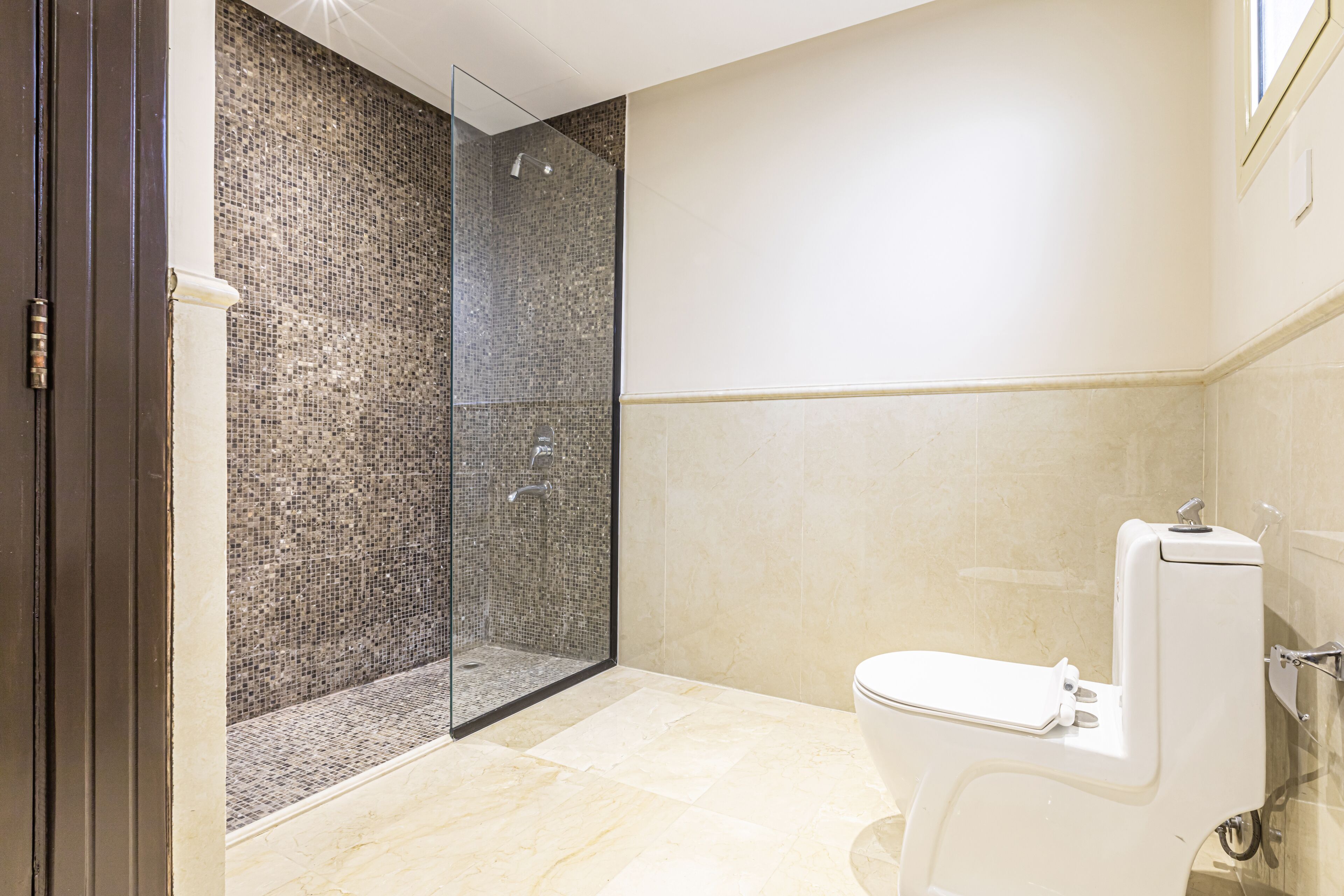A modern bathroom with a glass-enclosed shower, a toilet, and tiled walls.