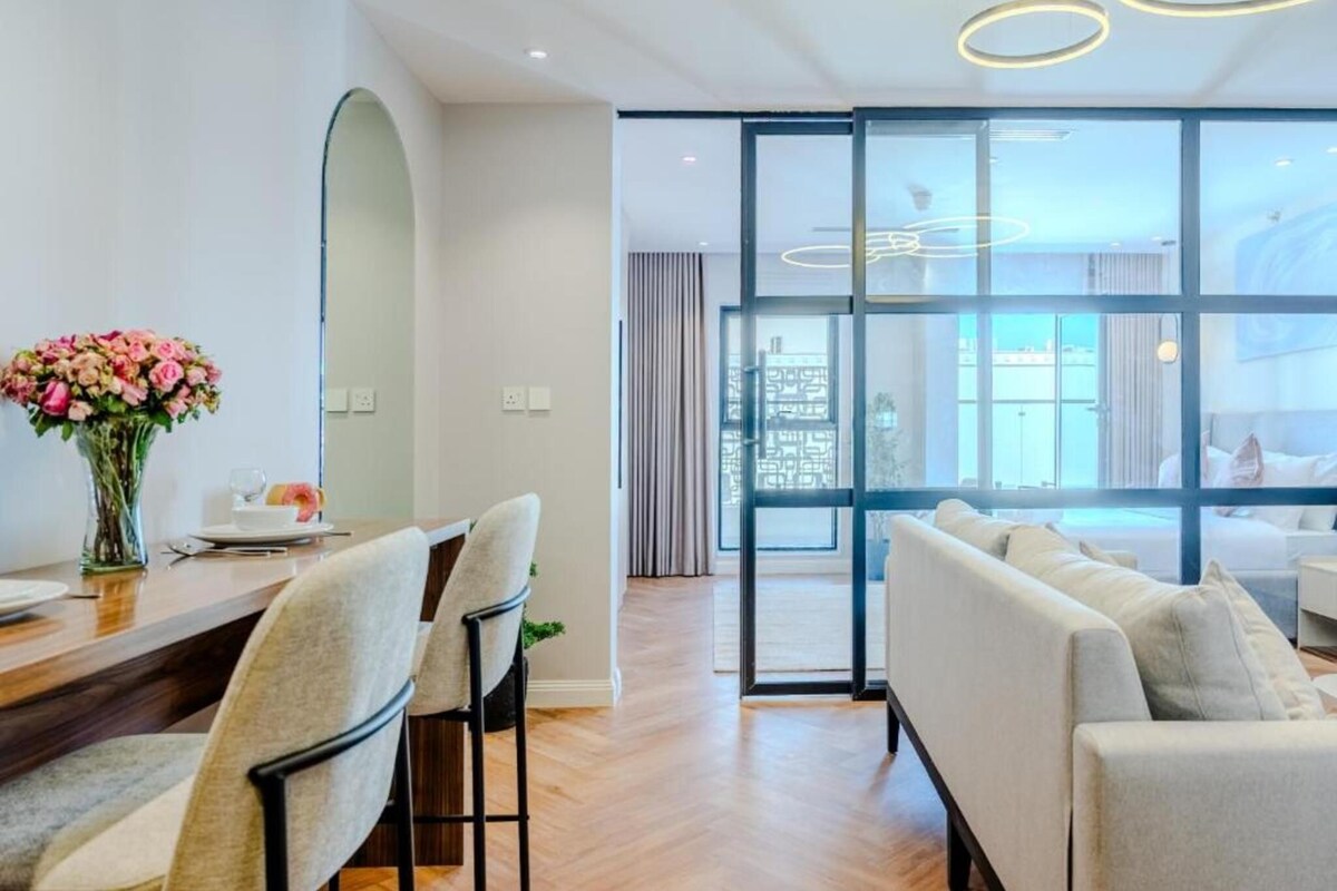 A modern hotel room with a dining area, a large window, and a sofa.