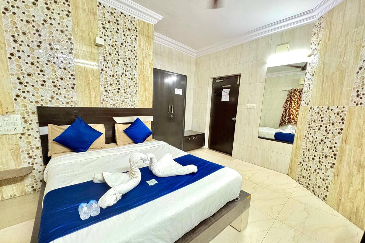 Habitación de hotel con cama, armario, espejo y baño.