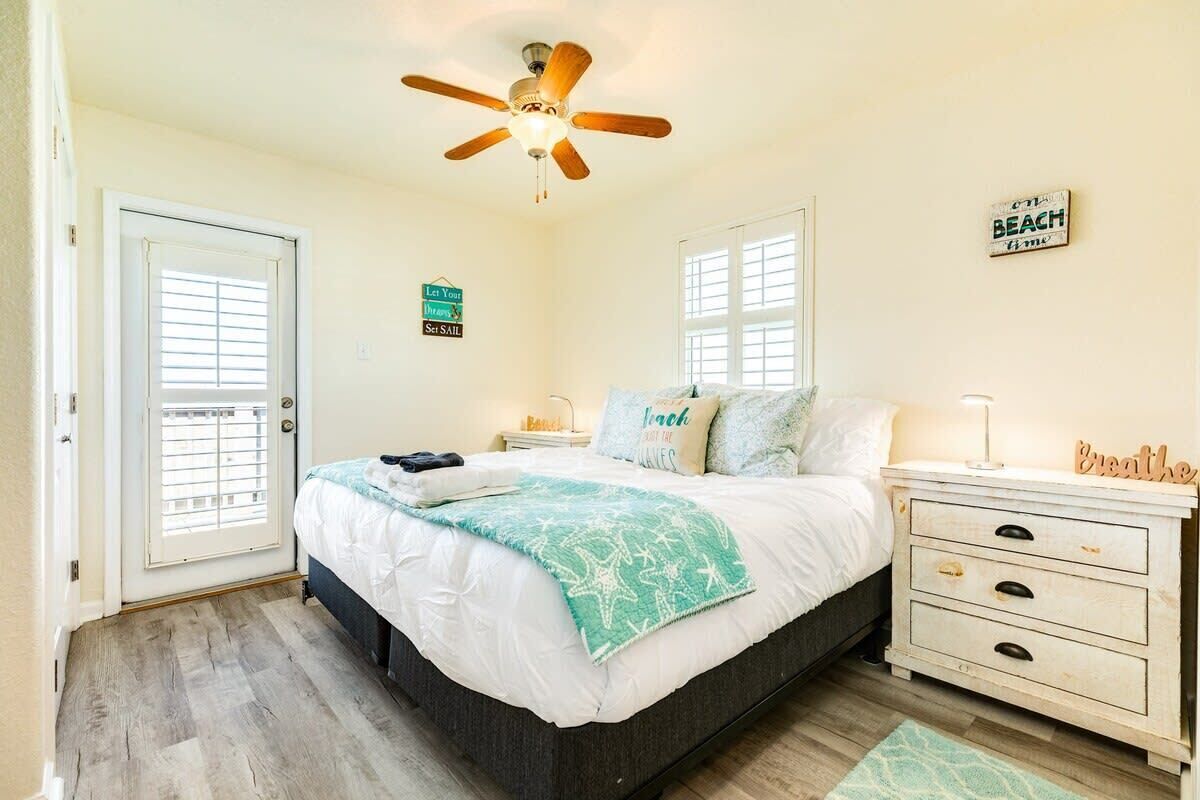 A bedroom with a bed, a ceiling fan, a nightstand, a dresser, and a window with blinds.