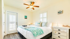 A bedroom with a bed, a ceiling fan, a nightstand, a dresser, and a window with blinds.