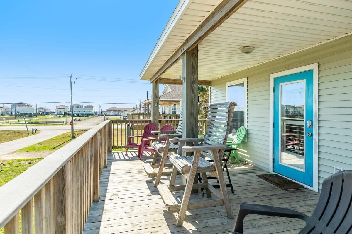 Une terrasse en bois avec des sièges d’extérieur, un porche couvert et une vue sur la plage et l’océan.
