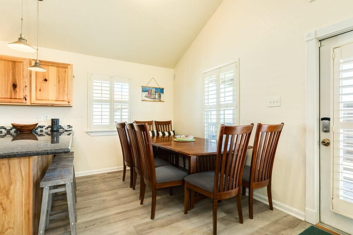 A dining area with a wooden table and chairs, a kitchen counter with stools, and a door with a window.